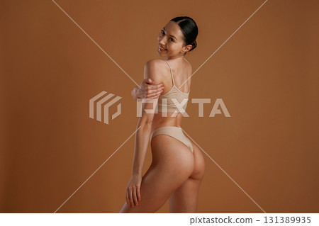 Back and side view. Woman with slim body shape is posing against background 131389935