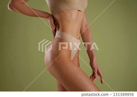 Side close up view. Woman with slim body shape is posing against background Side close up view. Woman with slim body shape is posing against background 131389956