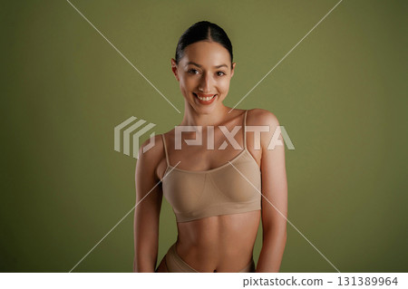 Smiling, cheerful facial expression. Woman with slim body shape is posing against background Smiling, cheerful facial expression. Woman with slim body shape is posing against background 131389964