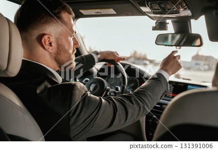 Driving, focused. Man in black suit is sitting in the car, driving Driving, focused. Man in black suit is sitting in the car, driving 131391006