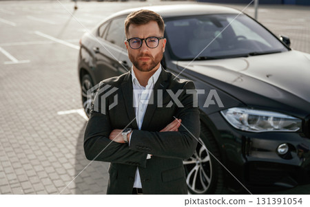 Black suit and white shirt. Businessman is near his car outdoors 131391054