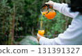 Hand holding jug pouring orange juice beverage 131391327