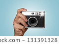 Hand holding vintage camera with flash on blue background 131391328
