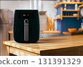 Modern black air fryer on wooden kitchen counter 131391329