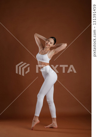 In white clothes. Beautiful fitness woman is in the studio In white clothes. Beautiful fitness woman is in the studio 131391459