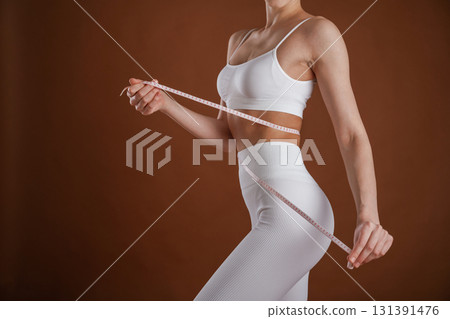 Weight loss and diet conception. With measuring tape. Beautiful fitness woman is in the studio 131391476