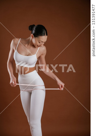 Weight loss and diet conception. With measuring tape. Beautiful fitness woman is in the studio 131391477