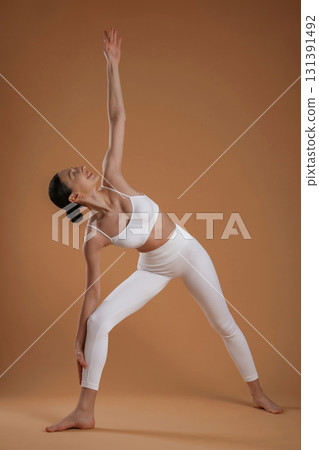 Doing stretching exercises. Beautiful fitness woman is in the studio Doing stretching exercises. Beautiful fitness woman is in the studio 131391492