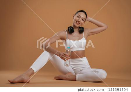 Black headphones on the neck. Beautiful fitness woman is in the studio 131391504