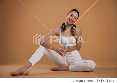 Black headphones on the neck. Beautiful fitness woman is in the studio Black headphones on the neck. Beautiful fitness woman is in the studio 131391505