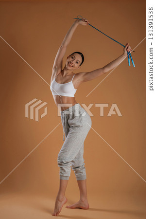 Jumping rope is in hands. Beautiful fitness woman is in the studio 131391538