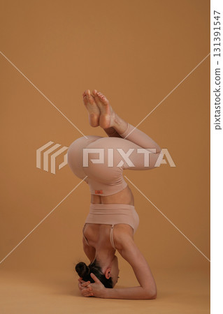 Doing headstand. Beautiful fitness woman is in the studio 131391547