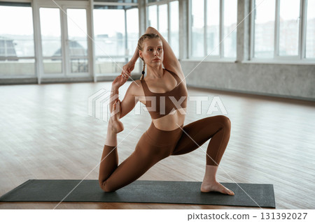 Front view. Warm up exercises. Fitness woman in sportswear is indoors Front view. Warm up exercises. Fitness woman in sportswear is indoors 131392027