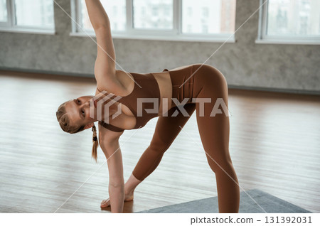 Turning the spine, exercise for back. Fitness woman in sportswear is indoors 131392031