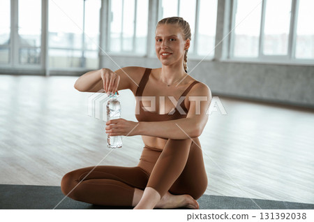 Sitting with bottle of water, break. Fitness woman in sportswear is indoors 131392038