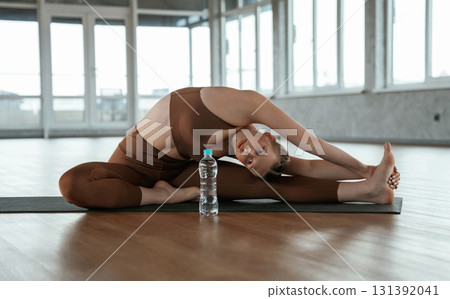 On the floor, doing stretching. Fitness woman in sportswear is indoors On the floor, doing stretching. Fitness woman in sportswear is indoors 131392041