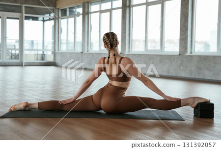 Twine exercises, sitting, wide stretching. Fitness woman in sportswear is indoors Twine exercises, sitting, wide stretching. Fitness woman in sportswear is indoors 131392057