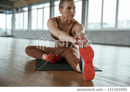 Stretching the legs. Fitness woman in sportswear is indoors 131392080