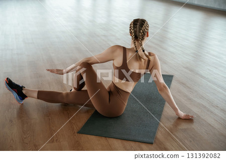 Turning the spine, exercise for back. Fitness woman in sportswear is indoors Turning the spine, exercise for back. Fitness woman in sportswear is indoors 131392082