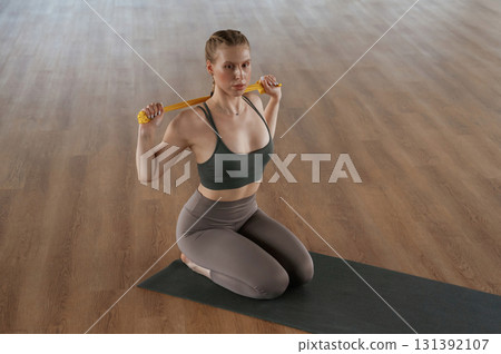 Doing stretches by using strap. Fitness woman in sportswear is indoors 131392107