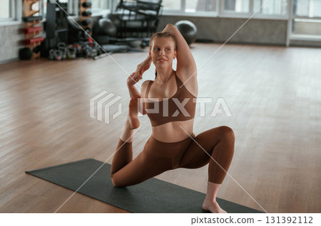 Front view. Warm up exercises. Fitness woman in sportswear is indoors Front view. Warm up exercises. Fitness woman in sportswear is indoors 131392112