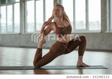 Flexible body, doing stretching. Fitness woman in sportswear is indoors 131392113