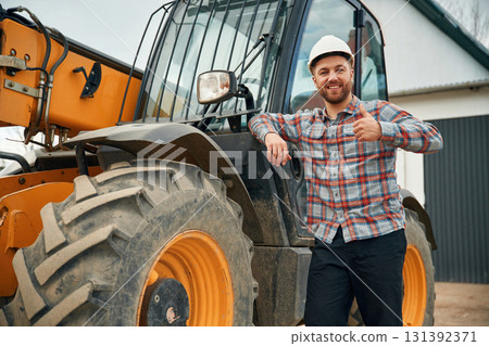 Leaning on the vehicle. Man is with tractor. Agricultural worker 131392371