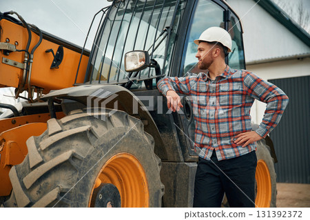 Leaning on the vehicle. Man is with tractor. Agricultural worker Leaning on the vehicle. Man is with tractor. Agricultural worker 131392372