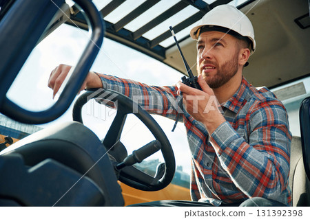 Walkie talkie device, conversation, orders. Man is with tractor. Agricultural worker 131392398