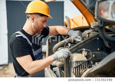 Doing maintenance. Man is with tractor. Agricultural worker Doing maintenance. Man is with tractor. Agricultural worker 131392399