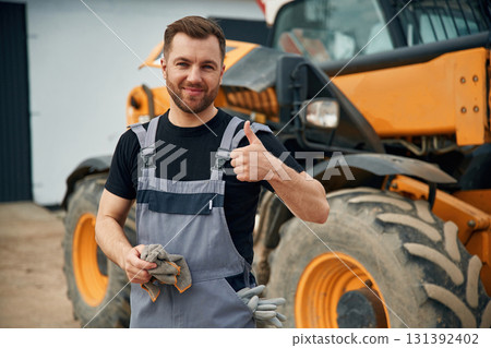 Job well done, with cloth to clean the hands. Man is with tractor. Agricultural worker Job well done, with cloth to clean the hands. Man is with tractor. Agricultural worker 131392402