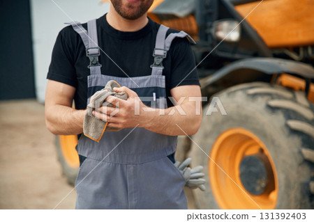 Cleaning the hands after job is done, mechanic. Man is with tractor. Agricultural worker Cleaning the hands after job is done, mechanic. Man is with tractor. Agricultural worker 131392403