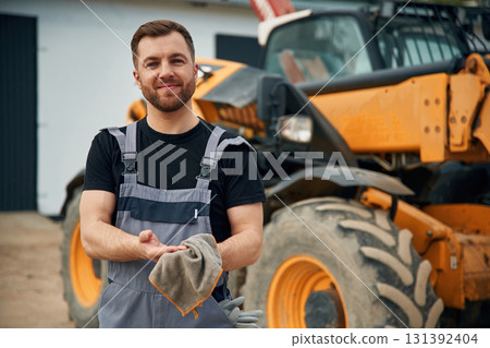 Cleaning the hands after job is done, mechanic. Man is with tractor. Agricultural worker Cleaning the hands after job is done, mechanic. Man is with tractor. Agricultural worker 131392404