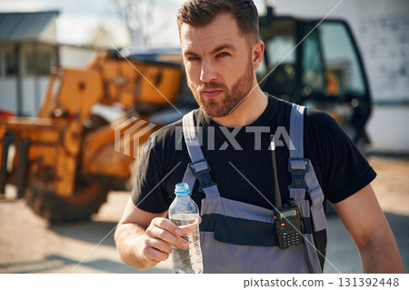 Drinking water, taking a break, tired. Man is with tractor. Agricultural worker 131392448