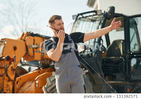 Communication with other people by walkie talkie. Man is with tractor. Agricultural worker 131392571