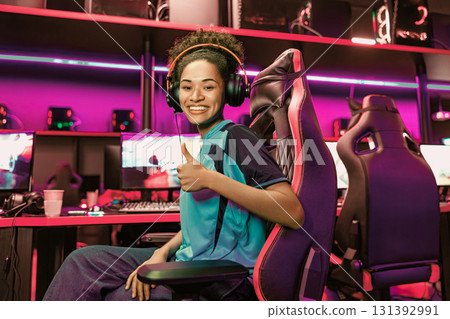 Excited Gamer in a Vibrant Modern Gaming Setup using a Headset for an Engaging Experience Excited Gamer in a Vibrant Modern Gaming Setup using a Headset for an Engaging Experience 131392991