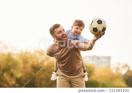 Real football, soccer ball. Happy father with son are having fun on the field at summertime Real football, soccer ball. Happy father with son are having fun on the field at summertime 131393103