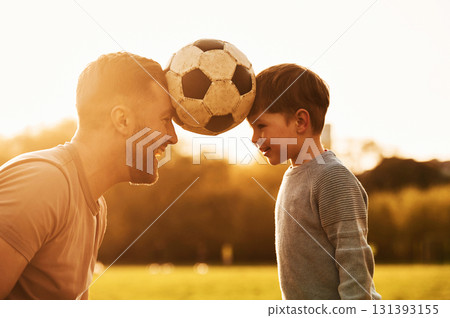 Positive emotions, holding soccer ball by heads. Happy father with son are having fun on the field at summertime Positive emotions, holding soccer ball by heads. Happy father with son are having fun on the field at summertime 131393155