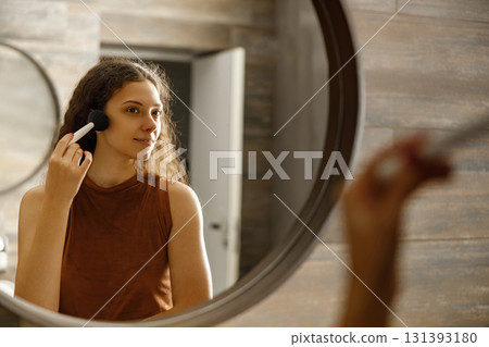 A Woman Applying Her Makeup in a Modern Bathroom Mirror to Enhance Her Natural Beauty A Woman Applying Her Makeup in a Modern Bathroom Mirror to Enhance Her Natural Beauty 131393180