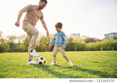 Playing soccer. Happy father with son are having fun on the field at summertime 131393378