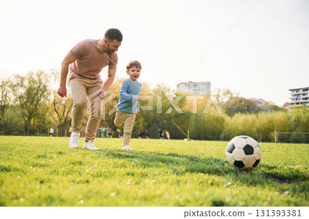 Playing soccer. Happy father with son are having fun on the field at summertime 131393381