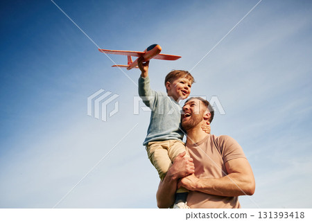 Father is holding son that playing with toy plane 131393418
