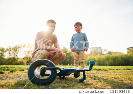 Little bicycle. Happy father with son are having fun on the field at summertime Little bicycle. Happy father with son are having fun on the field at summertime 131393428