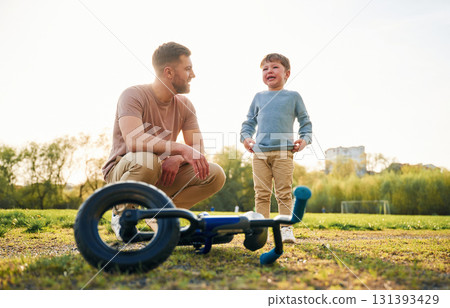 Little bicycle. Happy father with son are having fun on the field at summertime Little bicycle. Happy father with son are having fun on the field at summertime 131393429