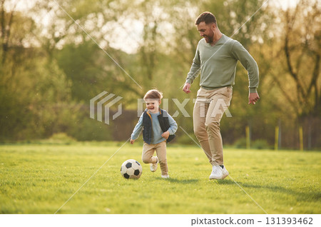 With soccer ball. Happy father with son are having fun on the field at summertime 131393462