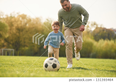 Learning to play soccer. Happy father with son are having fun on the field at summertime Learning to play soccer. Happy father with son are having fun on the field at summertime 131393464