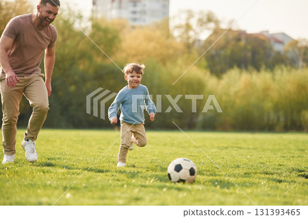 Learning to play soccer. Happy father with son are having fun on the field at summertime 131393465