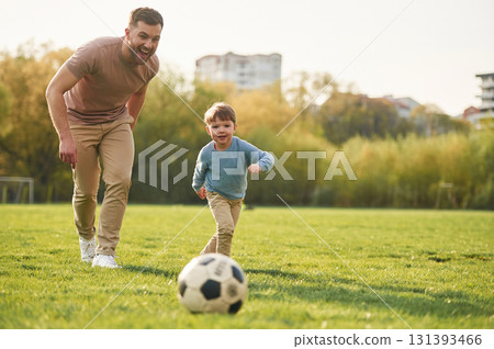 Learning to play soccer. Happy father with son are having fun on the field at summertime Learning to play soccer. Happy father with son are having fun on the field at summertime 131393466