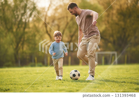 Learning to play soccer. Happy father with son are having fun on the field at summertime Learning to play soccer. Happy father with son are having fun on the field at summertime 131393468