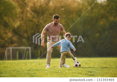 Learning to play soccer. Happy father with son are having fun on the field at summertime Learning to play soccer. Happy father with son are having fun on the field at summertime 131393469